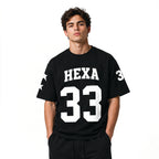 Hexa oversized baseball T-shirt in white with bold black lettering, relaxed fit, and short sleeves shown on a plain background.
